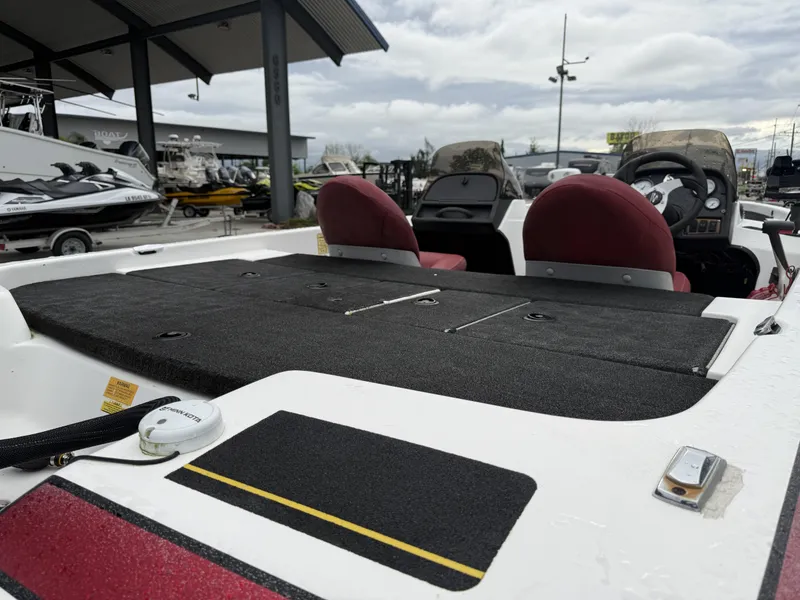 Slide: The Image of 2005 Skeeter SX 200 boat interior with red seats and dashboard, parked at a dealership. - 6