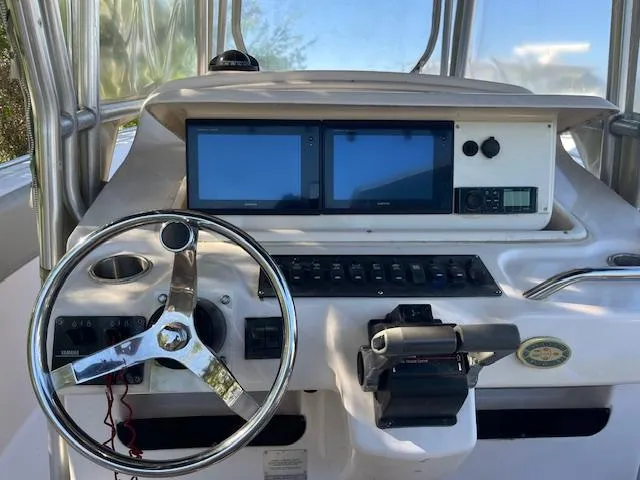 Slide: The Image of 2003 Grady-White 306 CC boat helm with dual screens and steering wheel. - 13