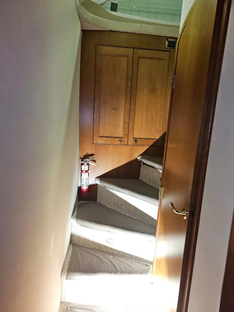 Slide: The Image of Staircase inside 2001 Cruisers Yachts 5000 Sedan Sport with wooden cabinets and fire extinguisher. - 15