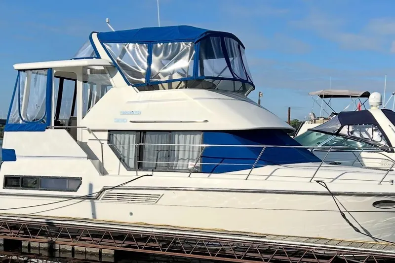 The Image of 1993 Carver 350 Aft yacht with blue canopy docked at marina. - 0