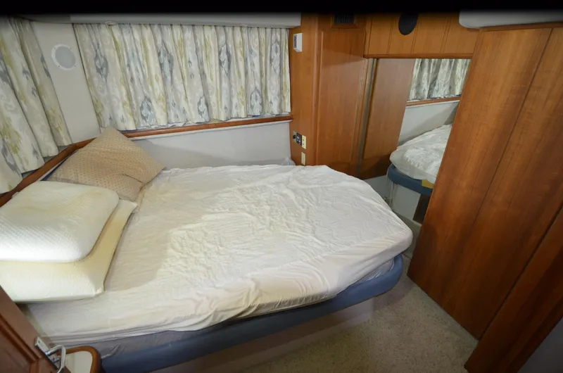Slide: The Image of 1993 Carver 350 Aft cabin interior with bed, wooden paneling, and floral curtains. - 12