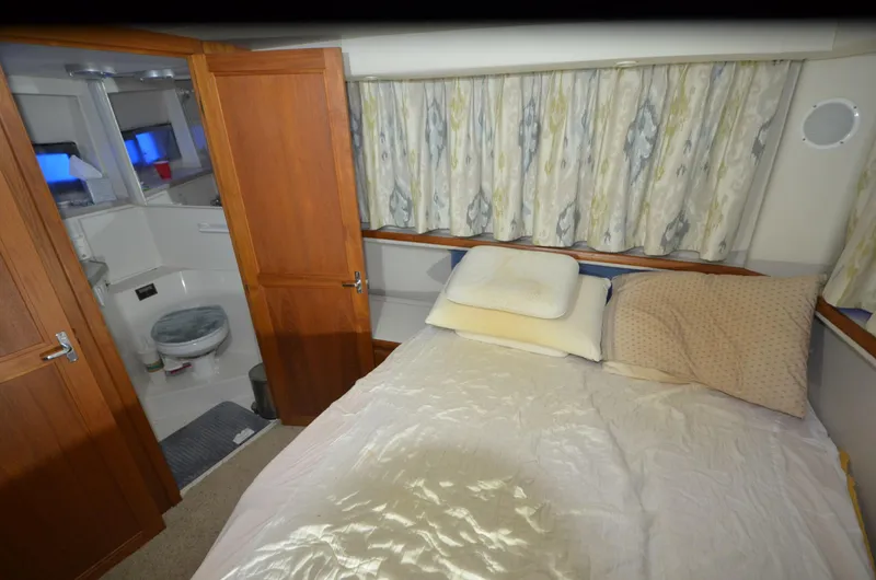 Slide: The Image of 1993 Carver 350 Aft cabin interior with bed, bathroom, and curtains. - 13