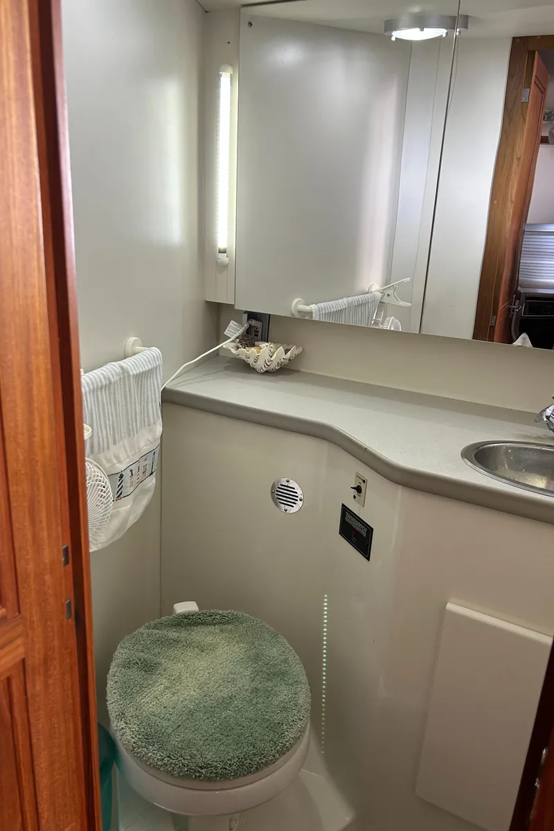 Slide: The Image of 1993 Carver 350 Aft bathroom with sink, mirror, and toilet featuring green cover. - 14