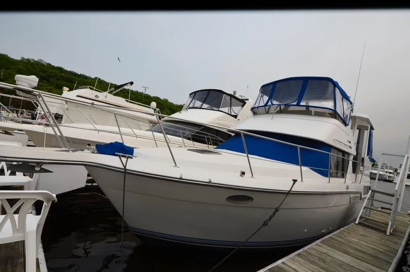 Slide: The Image of 1993 Carver 350 Aft yacht docked at marina, featuring blue accents and spacious design. - 18