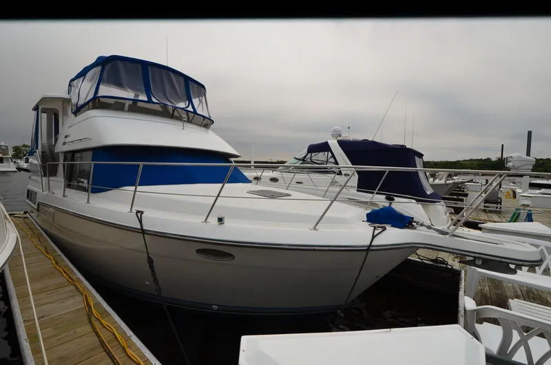Slide: The Image of 1993 Carver 350 Aft yacht docked at marina, featuring blue canopy and sleek design. - 19