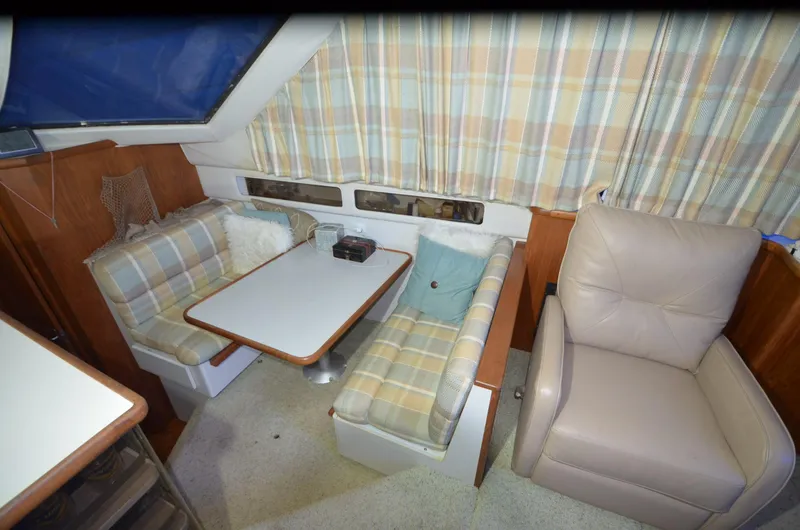 Slide: The Image of 1993 Carver 350 Aft cabin interior with plaid seating, table, and beige recliner. - 5