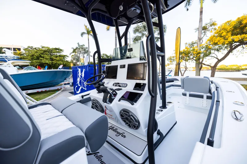 Slide: The Image of 2025 Yellowfin 26 Hybrid boat interior with modern controls and seating, docked near palm trees. - 3