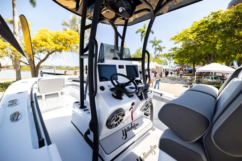 Slide: The Image of 2025 Yellowfin 26 Hybrid boat interior with modern controls, docked near palm trees. - 9