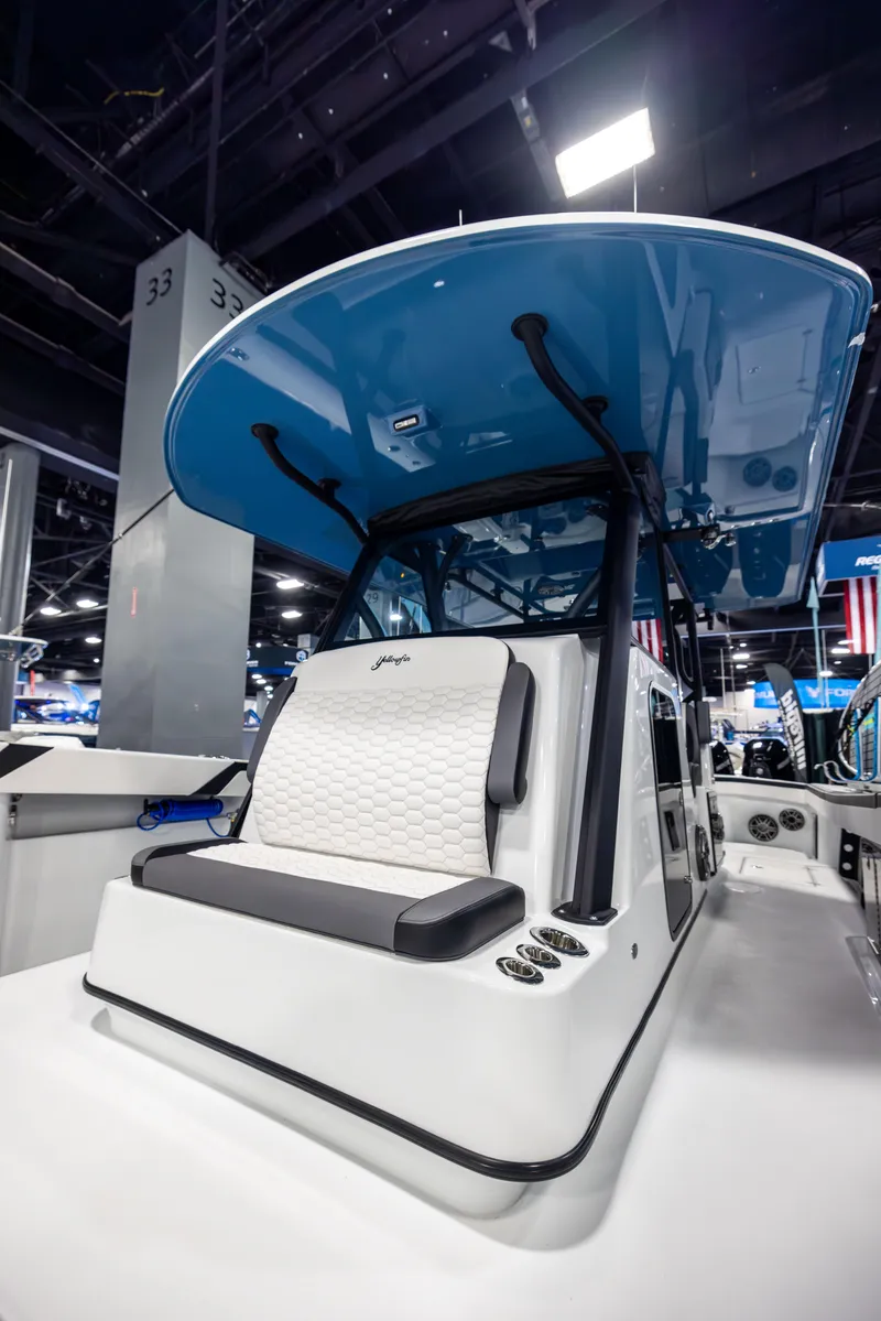 Slide: The Image of 2025 Yellowfin 39 Offshore boat with blue canopy and white seating, showcased indoors. - 15