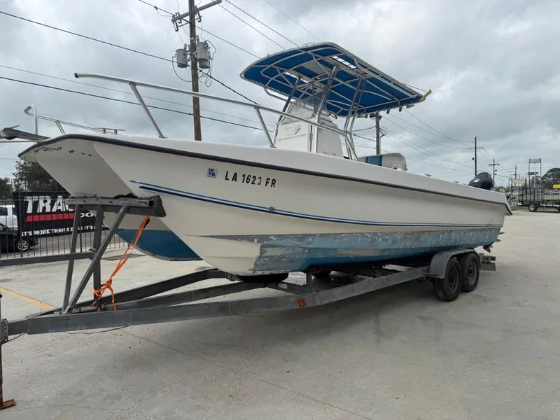 Slide: The Image of 2005 Twin Vee 26 Center Console boat on trailer, white and blue, parked outdoors. - 4