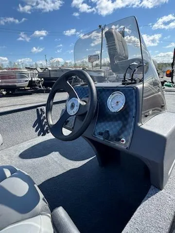 Slide: The Image of 2025 Tracker Bass Tracker Classic XL boat dashboard with steering wheel and gauges under a clear sky. - 9