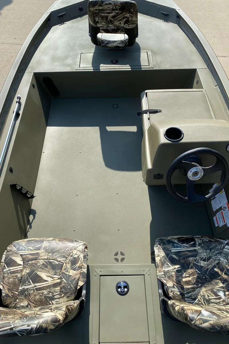 Slide: The Image of 2025 Tracker Grizzly 1754 SC boat interior with camo seats and steering console. - 4