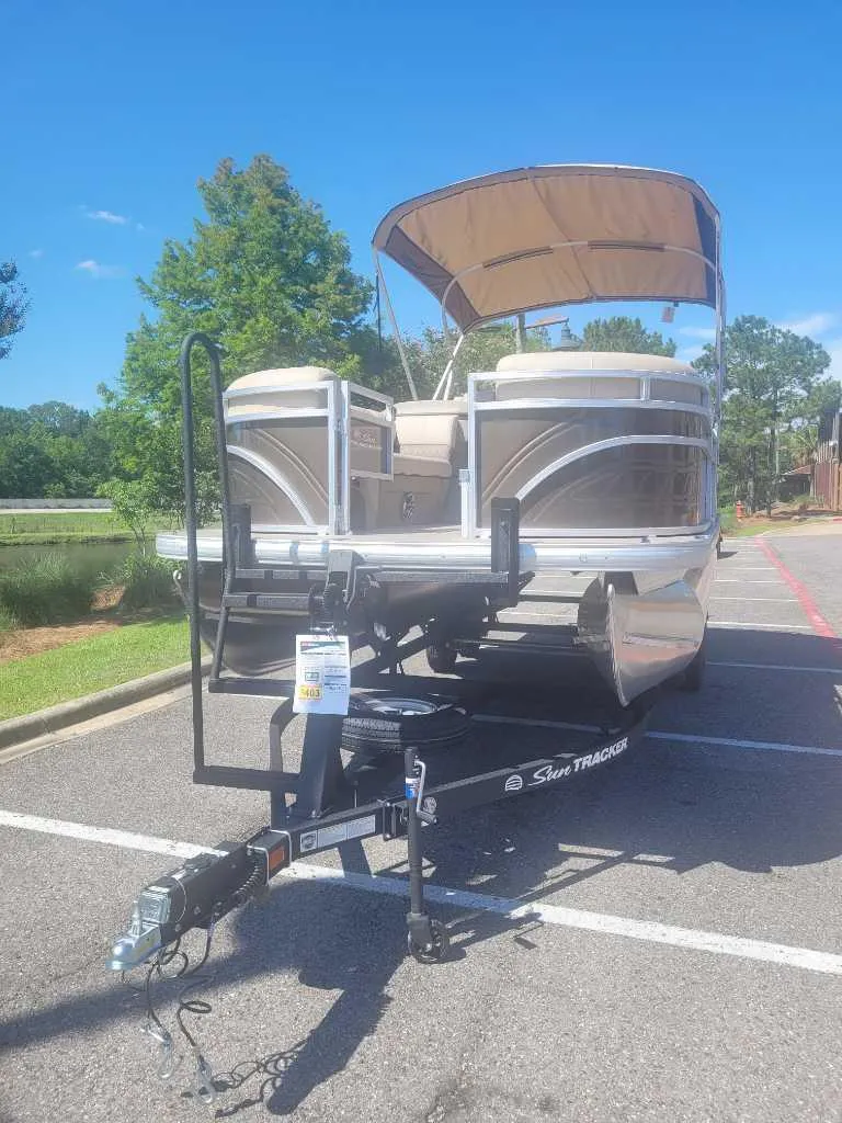 Slide: The Image of 2025 Sun Tracker SportFish 22 DLX pontoon boat with 150 HP engine, parked outdoors. - 3