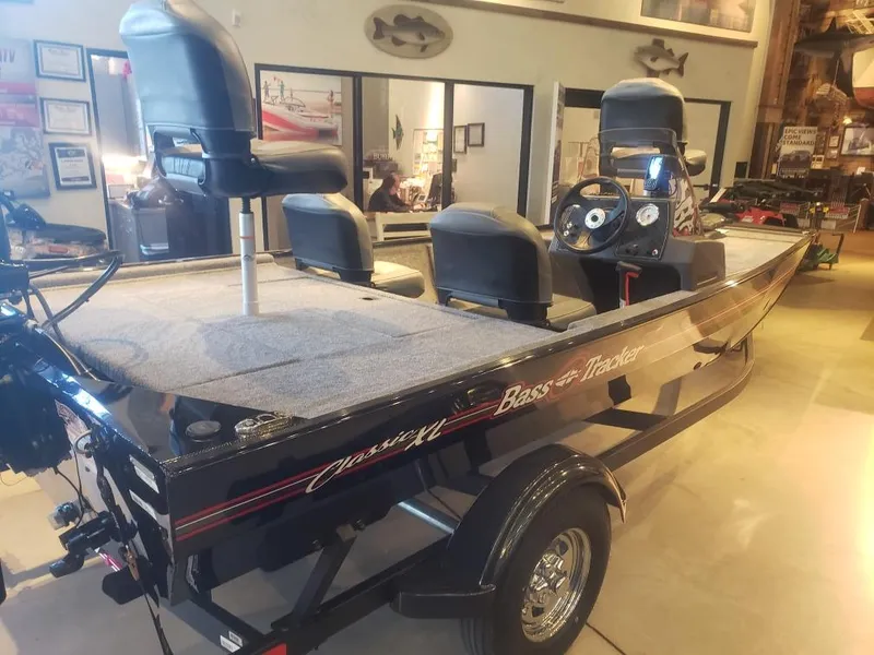 Slide: The Image of 2025 Tracker Bass Tracker Classic XL boat in showroom, featuring seating and control panel. - 13