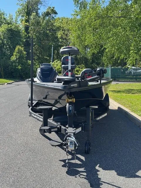 Slide: The Image of 2025 Tracker Savage 215 boat on trailer, parked on a sunny road with trees. - 2