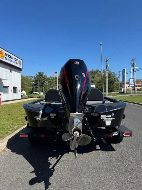 Slide: The Image of 2025 Tracker Savage 215 boat, rear view, parked near dealership under clear blue sky. - 3