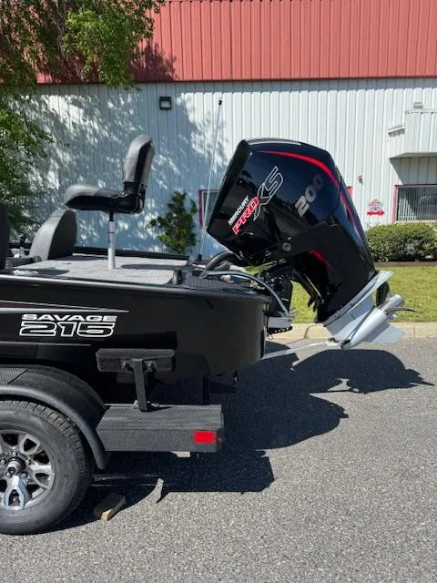 Slide: The Image of 2025 Tracker Savage 215 boat with powerful outboard motor, parked outdoors. - 4