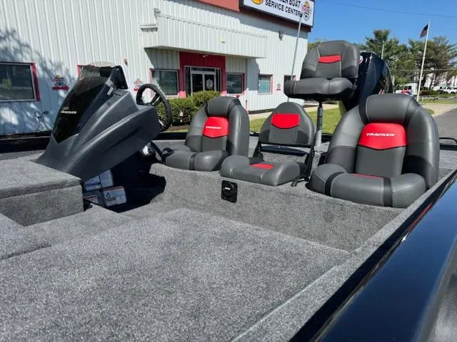 Slide: The Image of 2025 Tracker Savage 215 boat interior with red and black seats, parked outside a service center. - 7