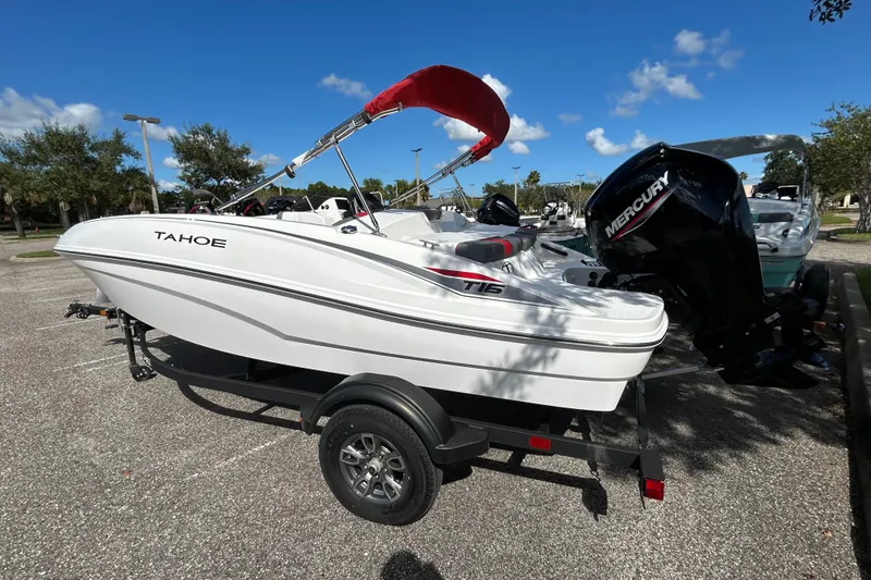 Slide: The Image of 2025 Tahoe T16 boat with Mercury engine on trailer, parked outdoors under blue sky. - 1