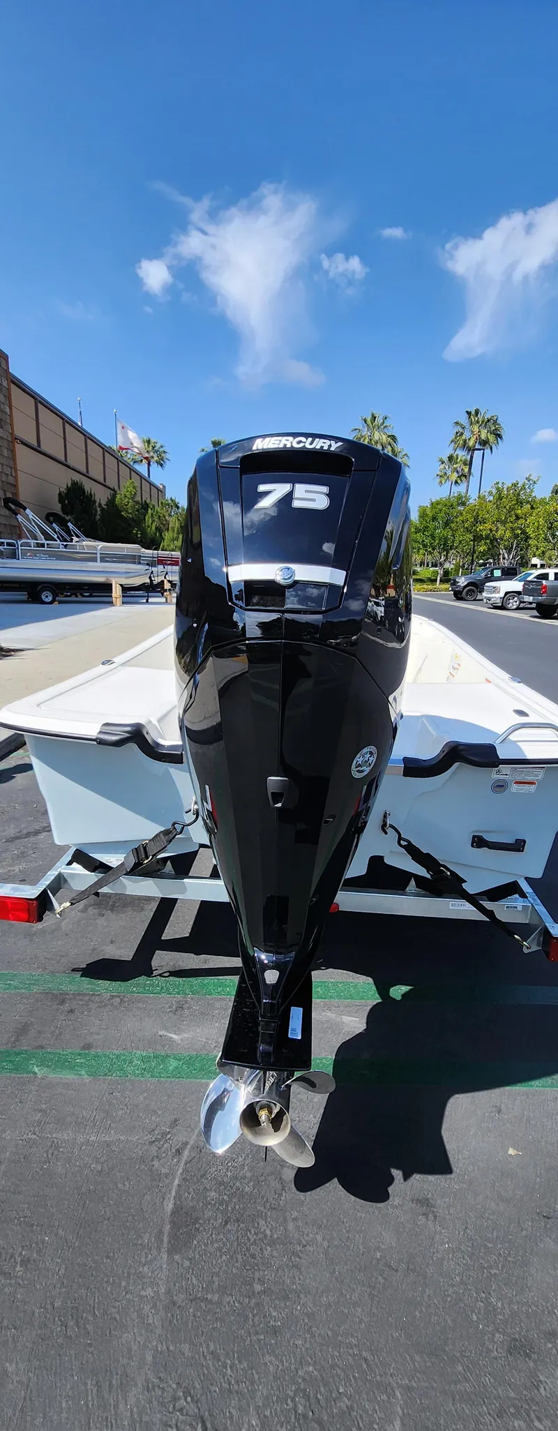 Slide: The Image of 2025 Mako Pro Skiff 17 CC with Mercury 75 engine, parked outdoors under clear sky. - 2