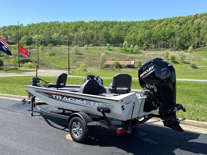 Slide: The Image of 2025 Tracker Pro Team 175 boat on trailer, parked outdoors with scenic green landscape. - 6