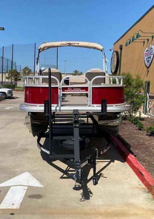Slide: The Image of 2025 Sun Tracker Bass Buggy 18 DLX pontoon boat parked on a trailer. - 3