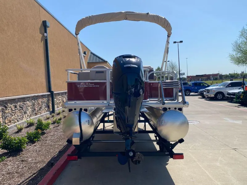 Slide: The Image of 2025 Sun Tracker Bass Buggy 18 DLX pontoon boat on trailer, parked outdoors. - 4