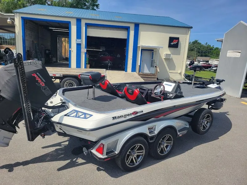 Slide: The Image of 2021 Ranger Z520L boat with triple-axle trailer parked outside a blue-roofed building. - 3
