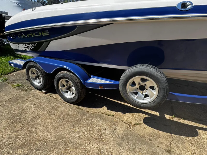 Slide: The Image of 2011 Tahoe Q7i boat on a dual-axle trailer, parked on concrete. - 18