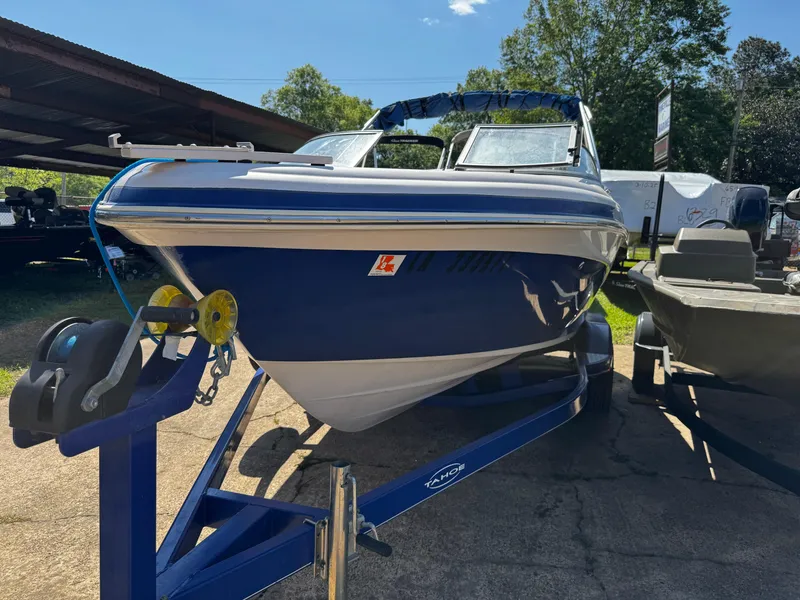 Slide: The Image of 2011 Tahoe Q7i boat on trailer, blue and white, parked outdoors. - 3