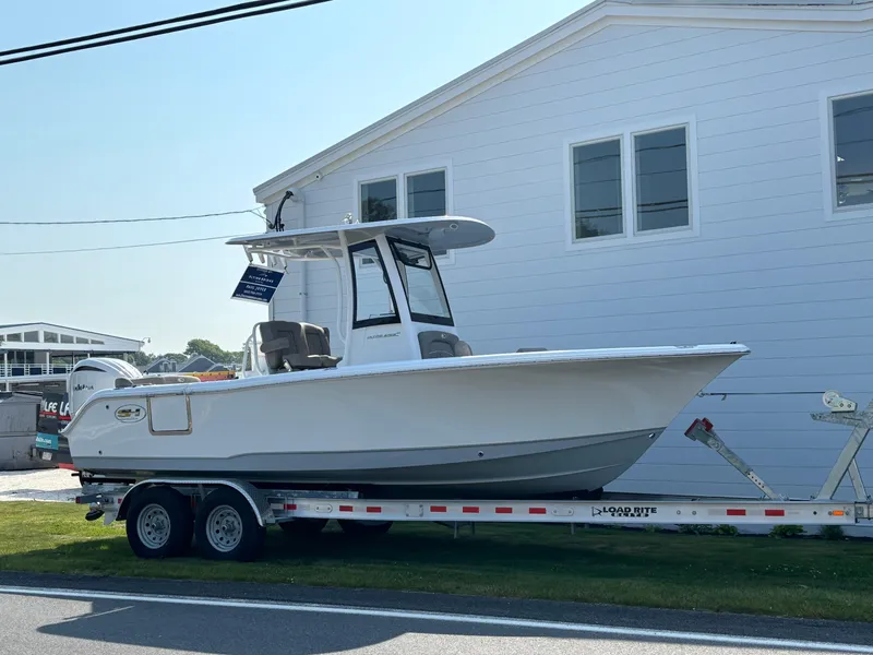 Slide: The Image of 2026 Sea Hunt Ultra 235 SE boat on trailer, parked beside a white building. - 1
