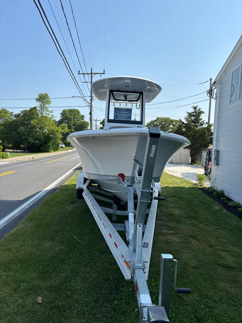 Slide: The Image of 2026 Sea Hunt Ultra 235 SE boat on trailer, parked beside a road. - 7
