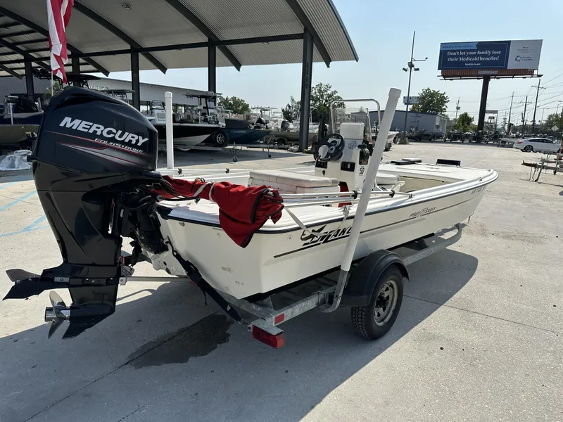 Slide: The Image of 2018 Mako 17 Pro Skiff boat with Mercury engine on trailer in outdoor setting. - 12