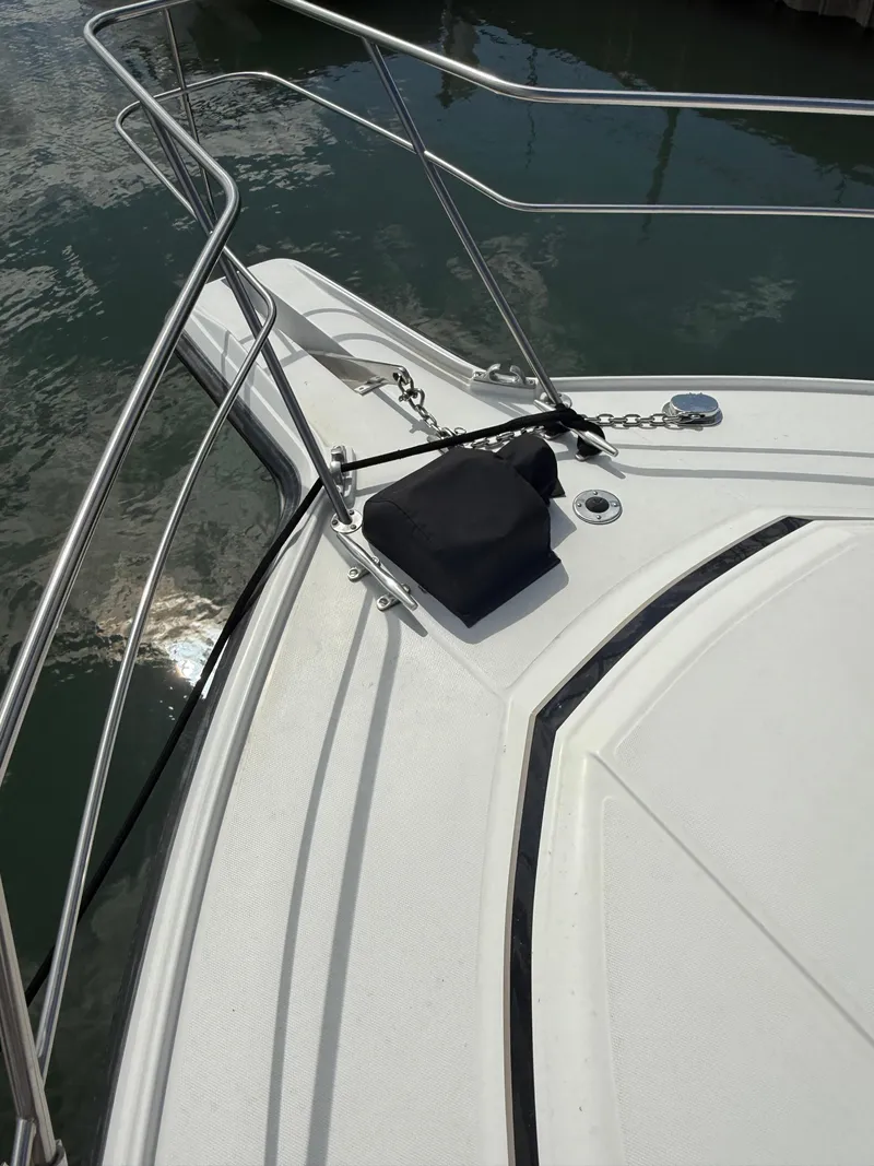 Slide: The Image of 1989 Phoenix 33 SFX boat bow with railing and anchor, docked on calm water. - 16