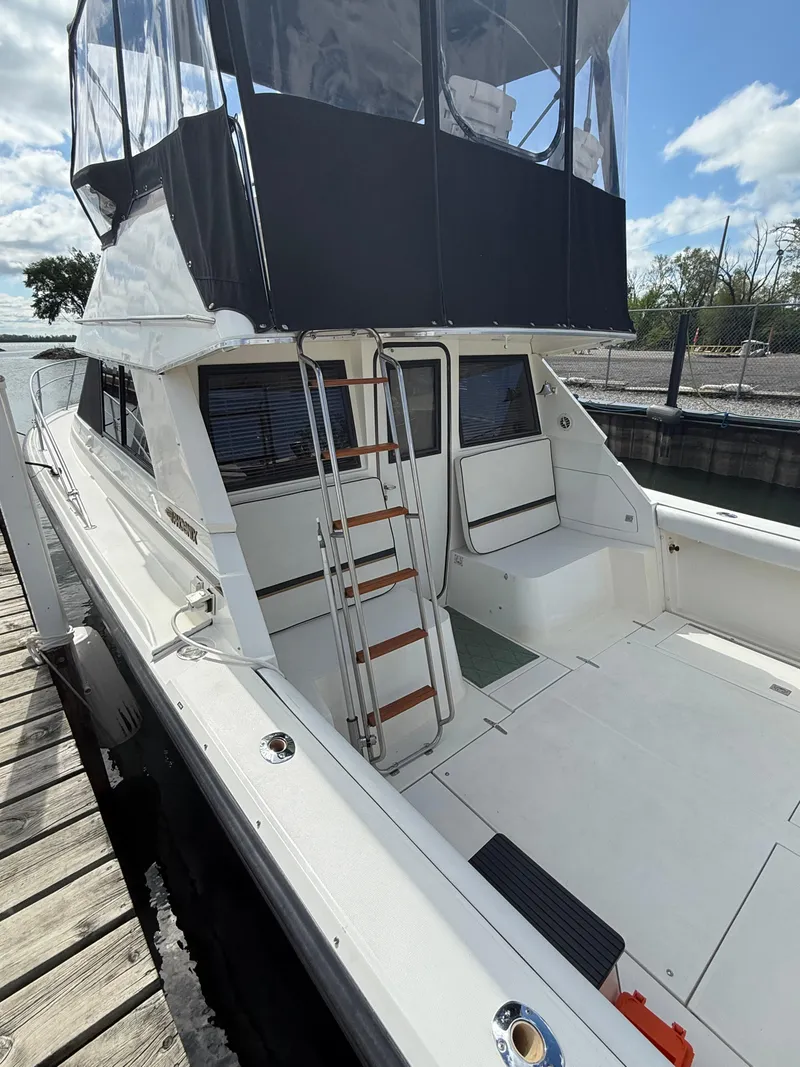 Slide: The Image of 1989 Phoenix 33 SFX boat docked, featuring a spacious deck and ladder to upper cabin. - 22