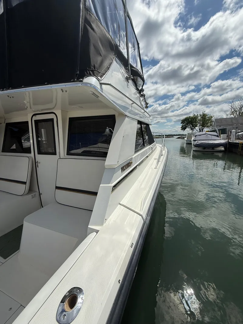 Slide: The Image of 1989 Phoenix 33 SFX boat docked on calm water under a partly cloudy sky. - 23