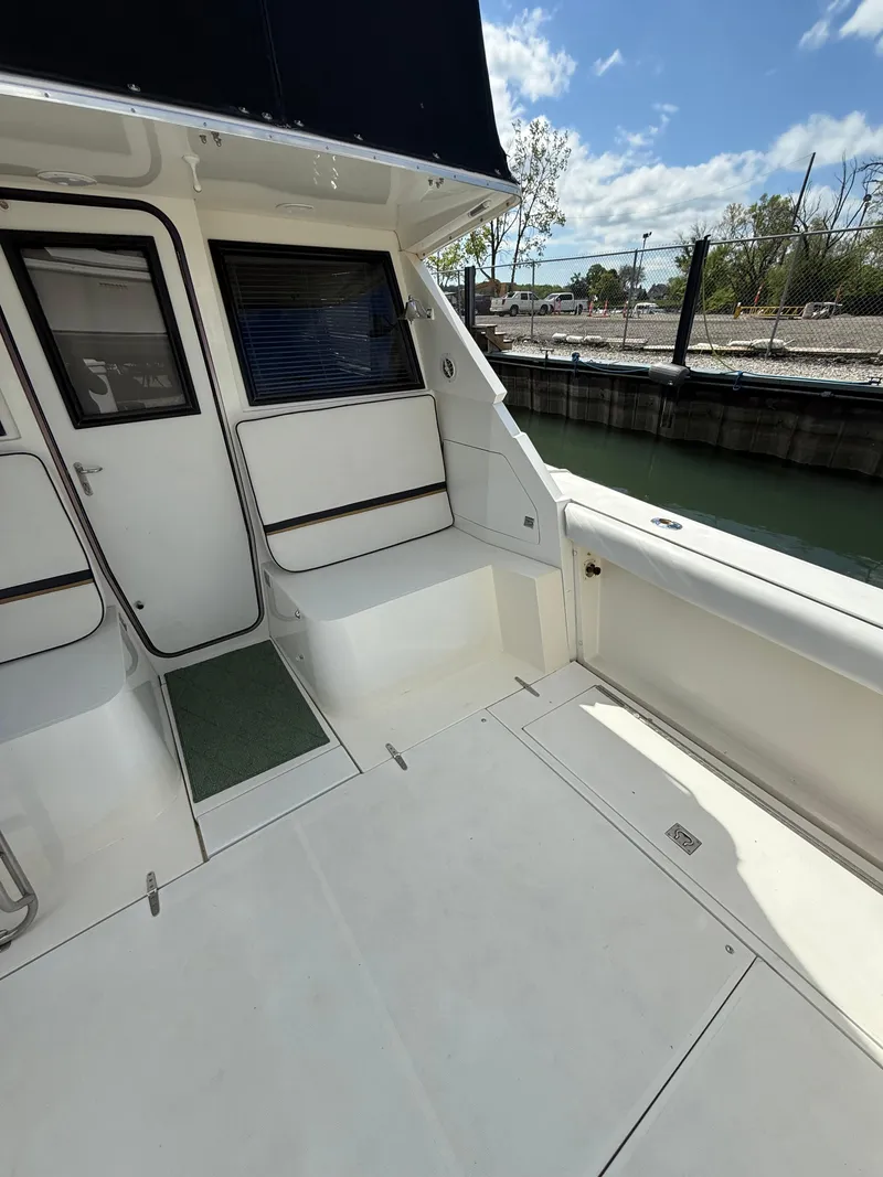 Slide: The Image of 1989 Phoenix 33 SFX boat deck with seating, docked by a calm waterfront. - 25