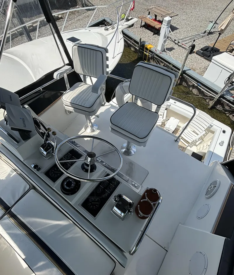 Slide: The Image of 1989 Phoenix 33 Sportfish boat cockpit with dual seats and steering wheel, docked outdoors. - 34