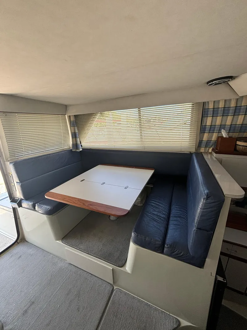 Slide: The Image of 1989 Phoenix 33 Sportfish interior with blue cushioned seating and a wooden table. - 39