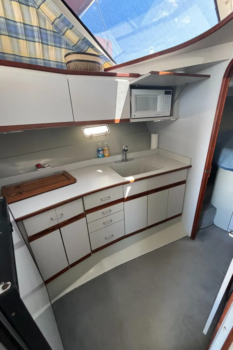 Slide: The Image of 1989 Phoenix 33 Sportfish boat kitchen with cabinets, sink, and microwave. - 47