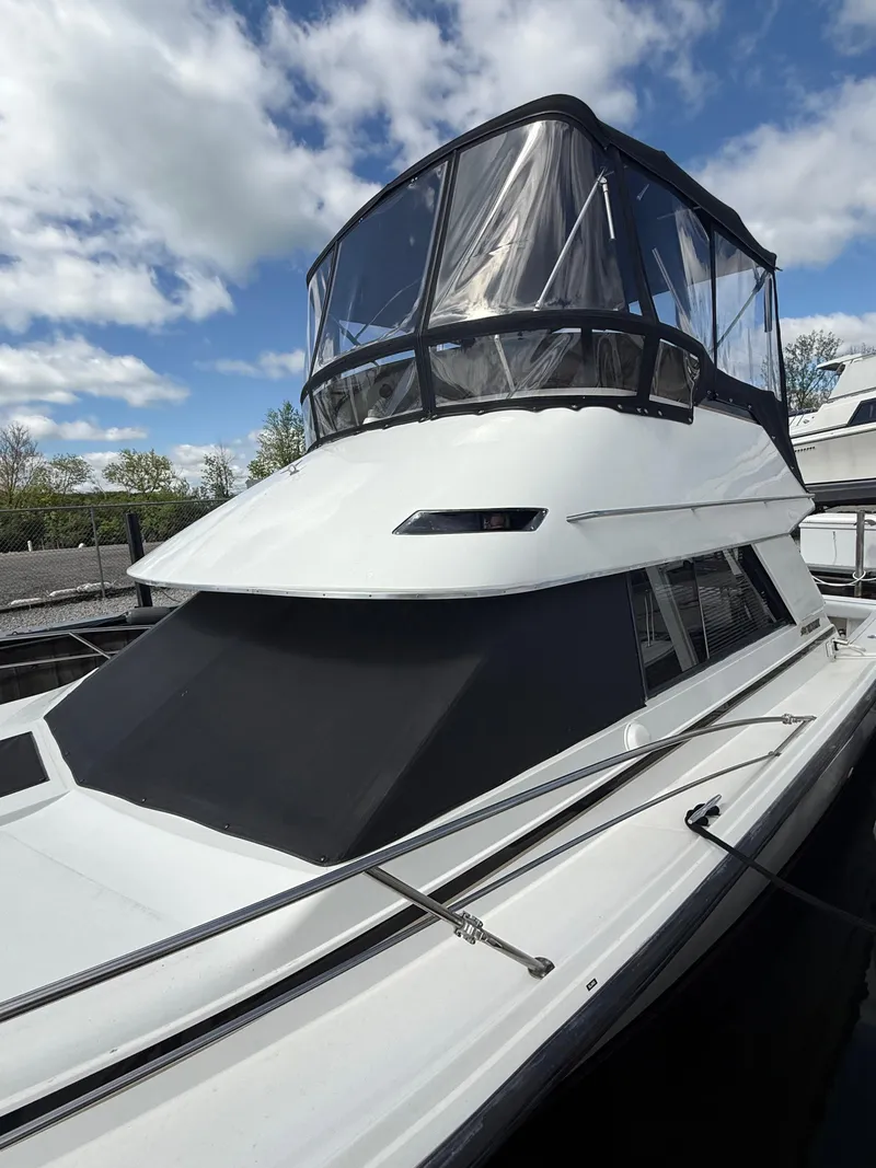 Slide: The Image of 1989 Phoenix 33 SFX boat with covered cabin, docked under a partly cloudy sky. - 9