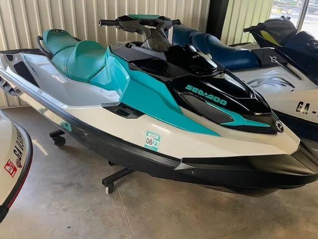 Slide: The Image of 2021 Sea-Doo GTX Pro jet ski in teal and black, parked indoors. - 1