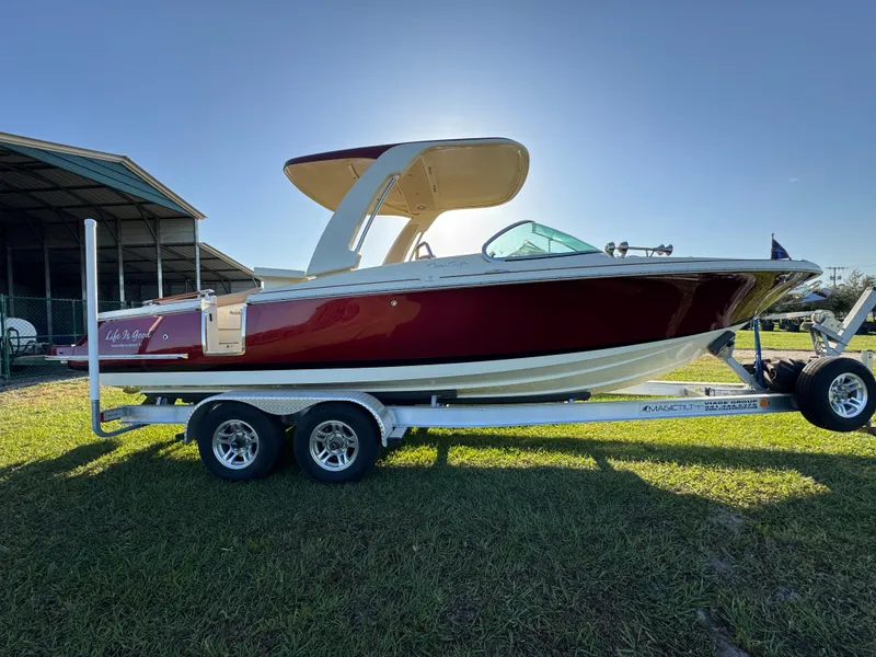 Slide: The Image of 2022 Chris-Craft Launch 25 GT boat on trailer, parked on grass under clear sky. - 3