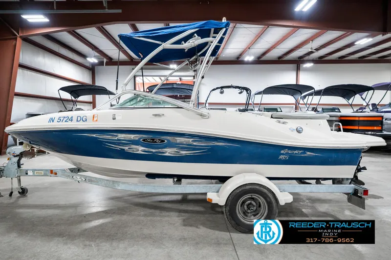 Slide: The Image of 2008 Sea Ray 185 Sport boat in showroom, blue and white, on trailer. - 11