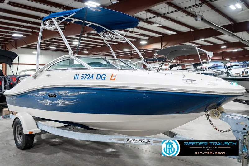 Slide: The Image of 2008 Sea Ray 185 Sport boat with blue hull on trailer in indoor showroom. - 6