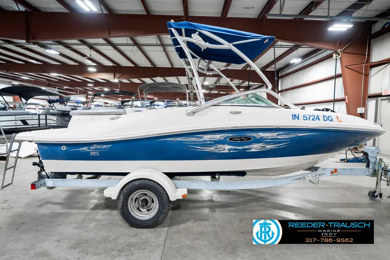 Slide: The Image of 2008 Sea Ray 185 Sport boat with blue and white design on a trailer in a showroom. - 7