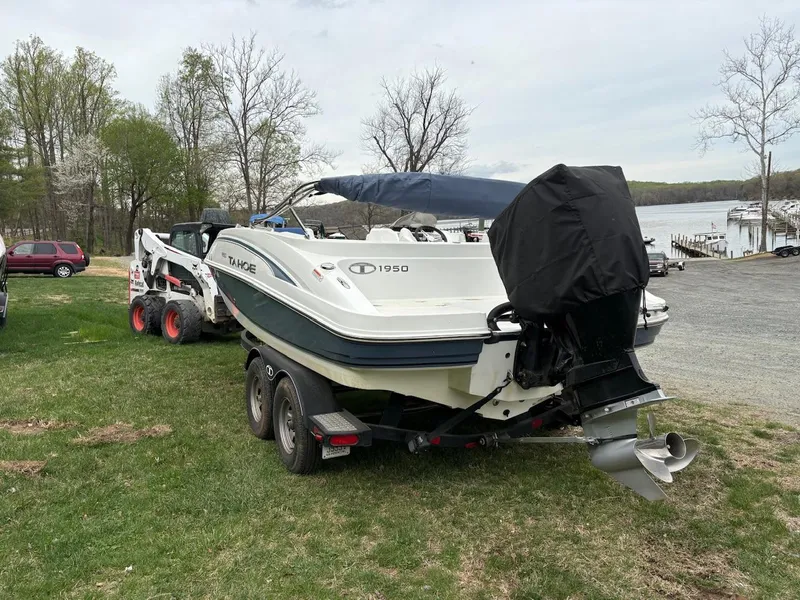 Slide: The Image of 2020 Tahoe 1950 boat on trailer, parked on grass near a lake. - 2