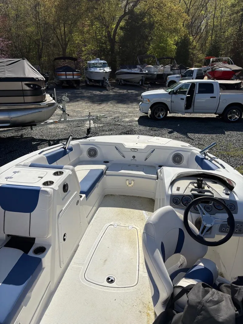 Slide: The Image of 2020 Tahoe 1950 boat interior with steering wheel, parked in a marina with trucks and boats. - 7