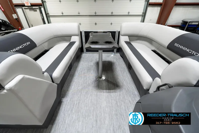 Slide: The Image of 2025 Bennington 20 SSR boat interior with gray seating and table, showcased in a showroom. - 22