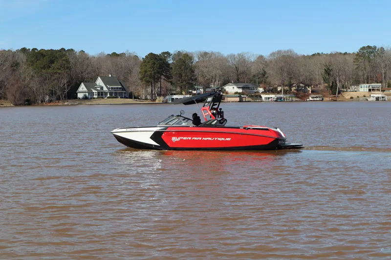 Slide: The Image of 2018 Nautique Super Air Nautique G25 boat cruising on a lake with houses in the background. - 4